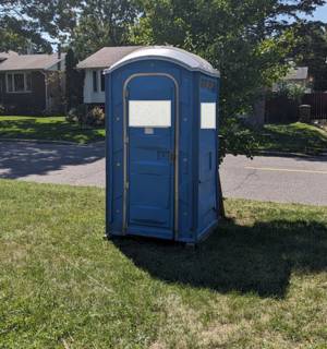 Portable toilet on a lawn near the street